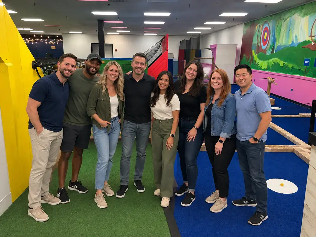 Team poses on an indoor mini golf course at Mr. Putters in Tampa, FL, during a company milestone celebration